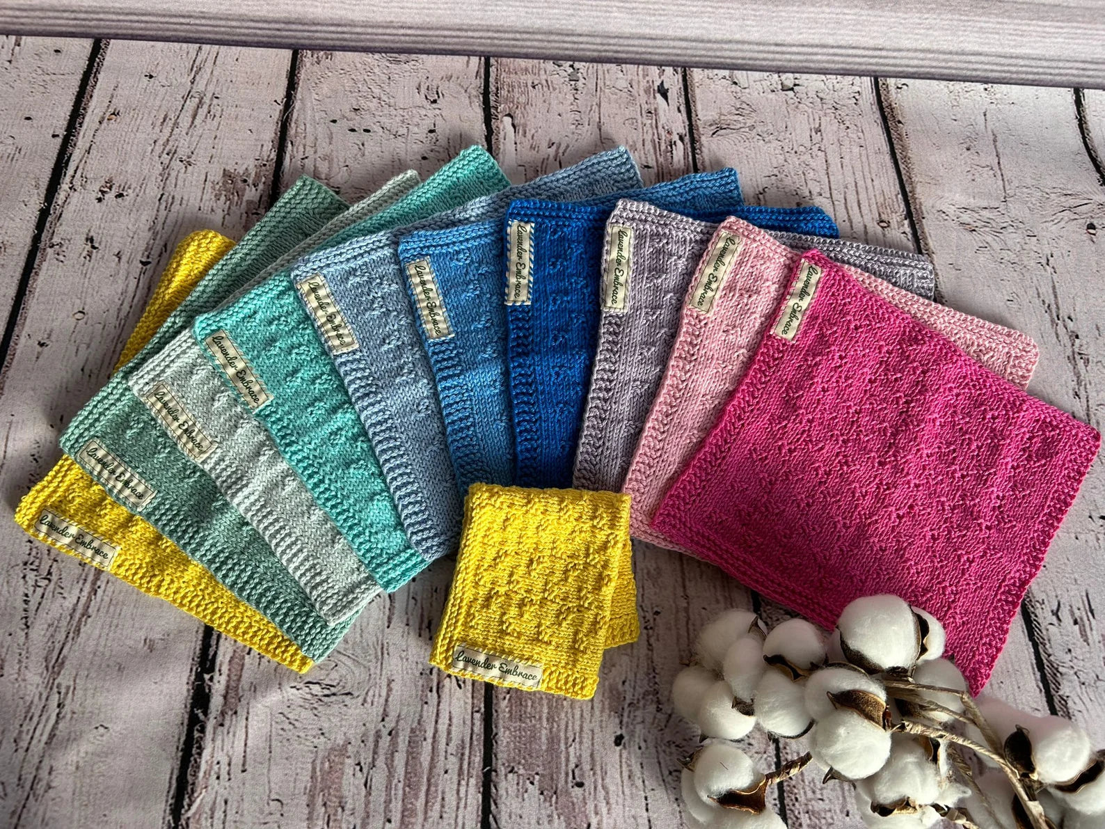 Colorful knitted squares on a wooden surface with cotton balls.