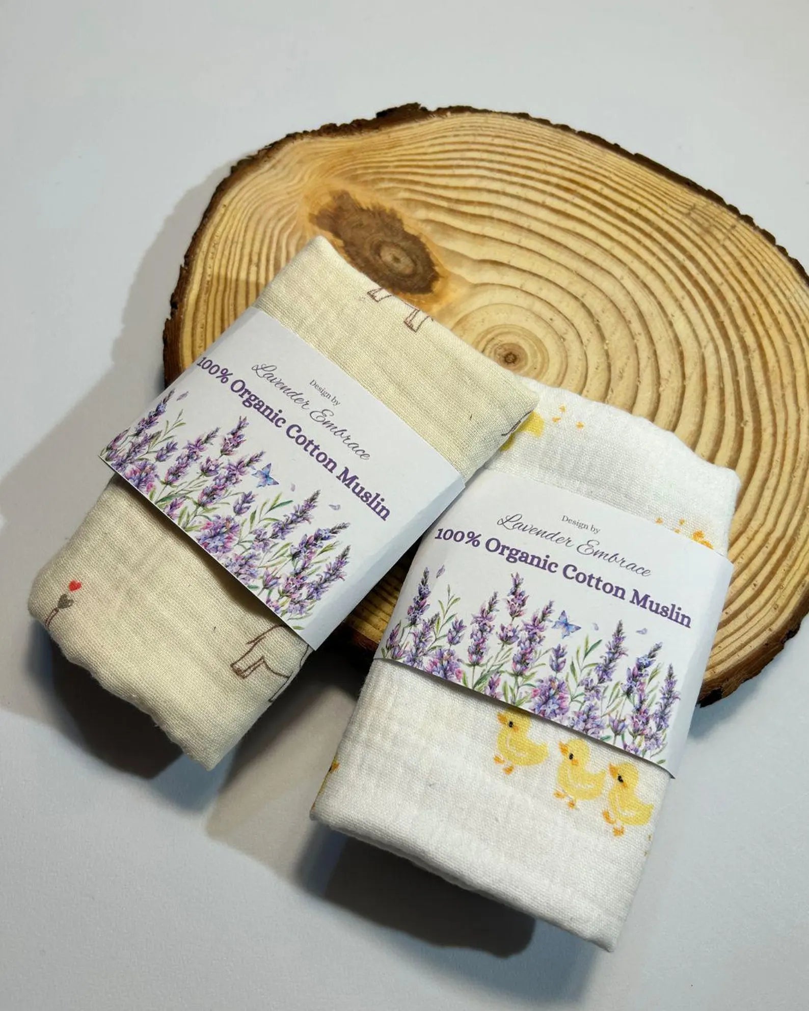 Two organic cotton muslins with labels on a wooden log