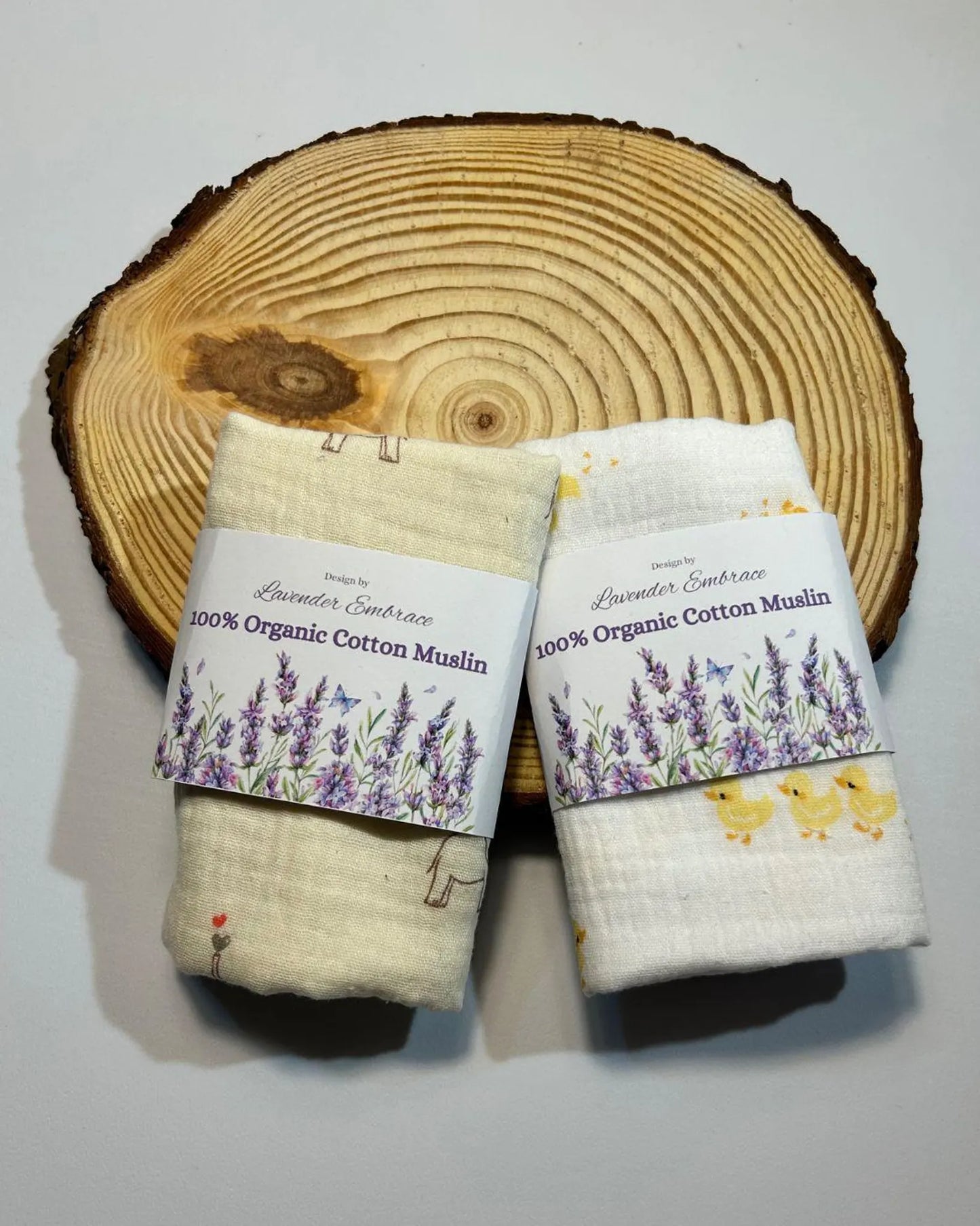 Two organic cotton muslin wraps with labels on a wooden surface