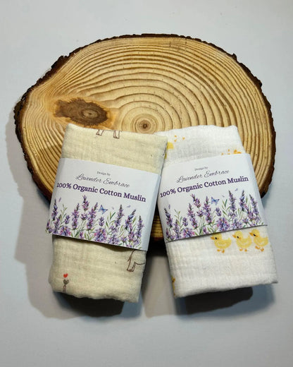 Two organic cotton muslin wraps with labels on a wooden surface